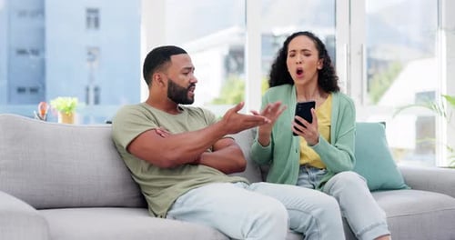 Couple Arguing on Sofa with Mobile Phone