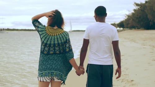 Young couple holding hands walking on a beautiful beach in Australia