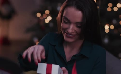 Woman Opening Christmas Gift with Joyful Smile
