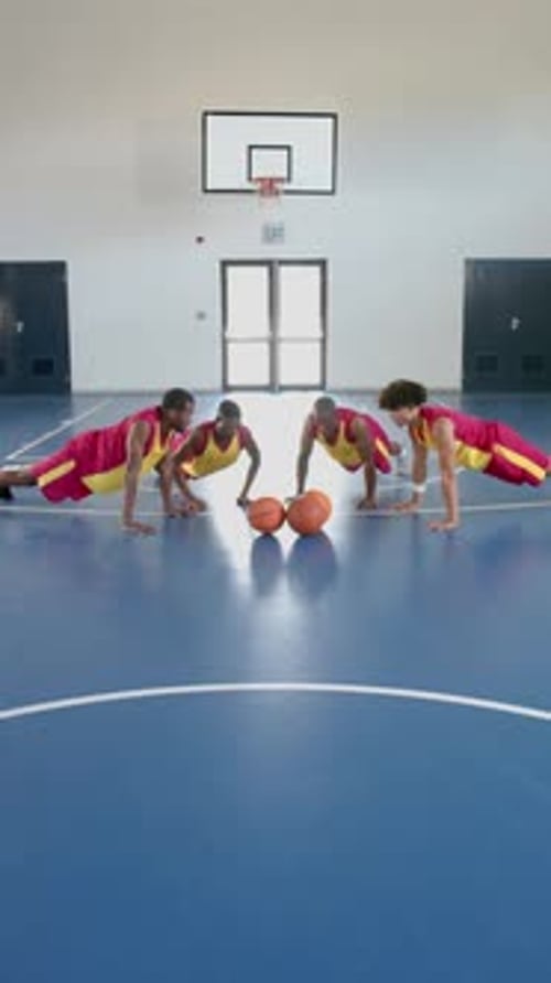 Vertical video: Basketball players doing push-ups on court during training session in gym, copy spac