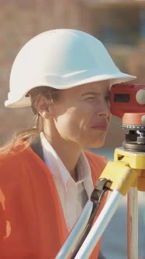 Woman Civil Engineer Surveys with Theodolite on Construction Site