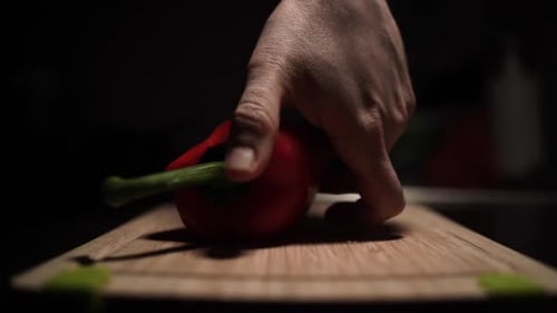 Cutting Red Bell Pepper with Knife on Board