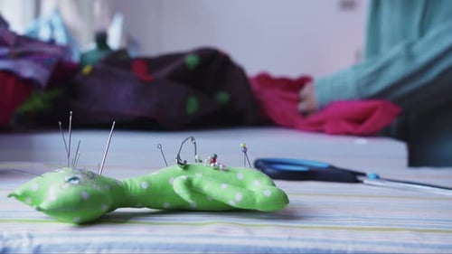Eine Näherin steckt eine Stecknadel in eine Nadelpuppe