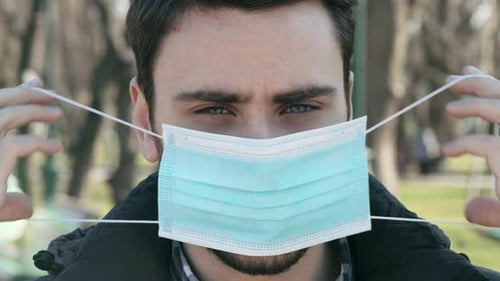 Young Man Puts on Surgical Mask Close Up