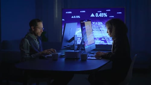 Man and Woman Working on Computers at Night