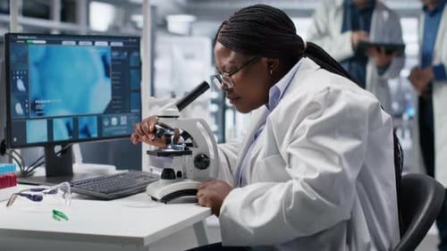 African American Scientist Placing Tray Under the Microscope