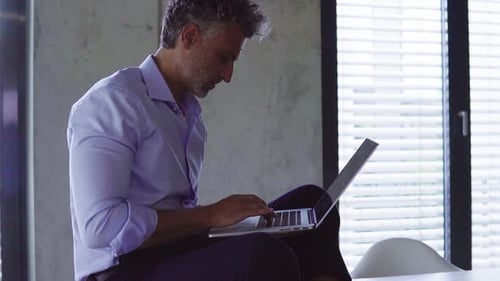 Mature businessman works confidently at his wooden desk in a sunny creative office