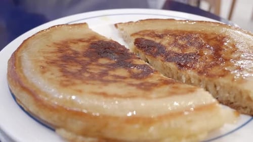 Close-up of golden-brown pancake topped with syrup, showcasing its texture and freshness
