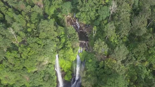 Aerial tilt from top of Bali jungle waterfall with several cascades