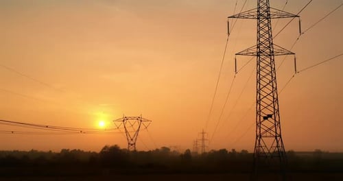 Aerial view of electric power pylons at sunset. Concept of: pollution, renewable energy, electrici