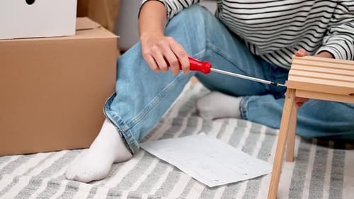 Adult Assembling Wooden Table with Screwdriver Indoors