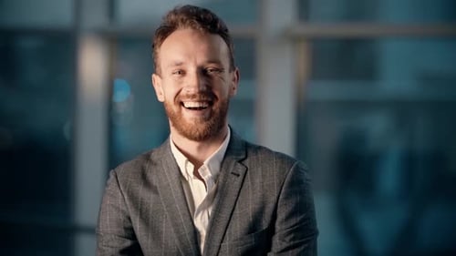 close-up portrait of a smiling young man in the office with panoramic windows with night city view