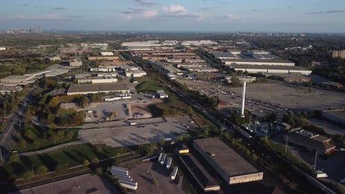 Statische Luftaufnahme eines Industriegebiets zur Goldenen Stunde. Der Zug bewegt sich in der Mitte des Rahmens. Bi