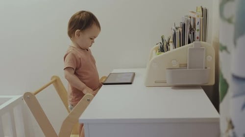 Toddler Interacts with Tablet at Desk in Home