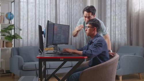 Asiatischer Vater schreit seinen Sohn an, während er einen Softwareingenieur entwickelt, der App und ein Programm entwickelt