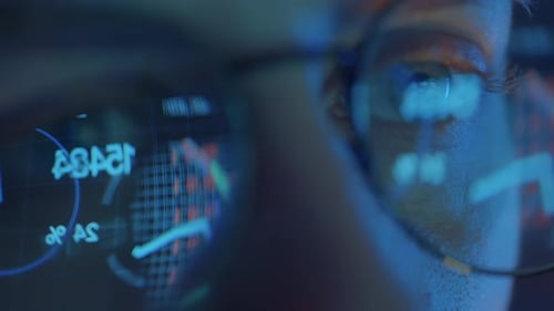Trader Wearing Glasses is Working on Laptop Computer Screen with Stock Market Charts and Bitcoin BTC