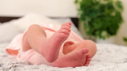Tiny Baby Feet Kicking on Soft White Blanket