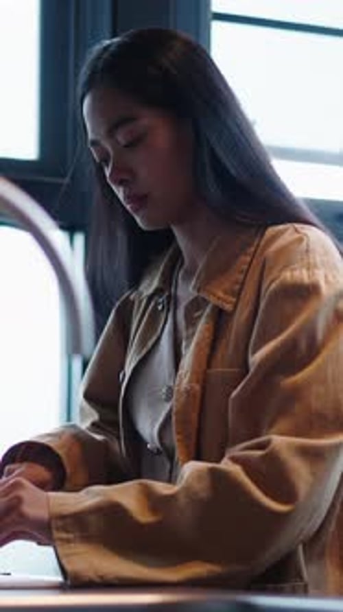Young Asian Woman Carefully Cutting Fresh Lime on a Wooden Cutting Board in a Kitchen