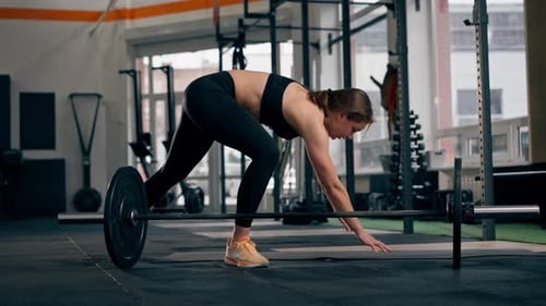 In the Gym Girl Trainer Does Lunges on the Floor After Working with a Barbell Jumping While Lying