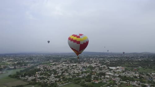 Aerial view towards a hot air balloon flying over a gloomy city - approaching, drone shot