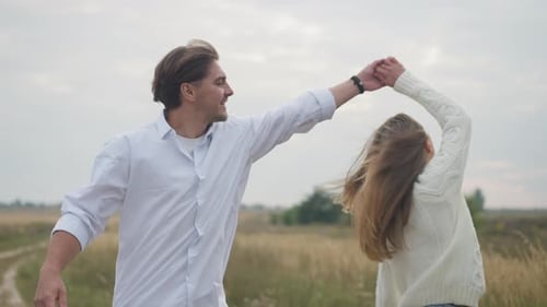 Couple Walking and Holding Hands in Rural Field