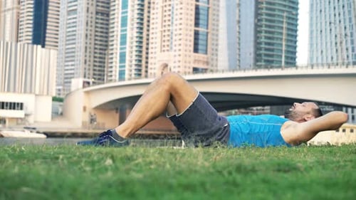 Tired Man Exercising, Doing Crunches on Grass in Park and Taking Break 30s
