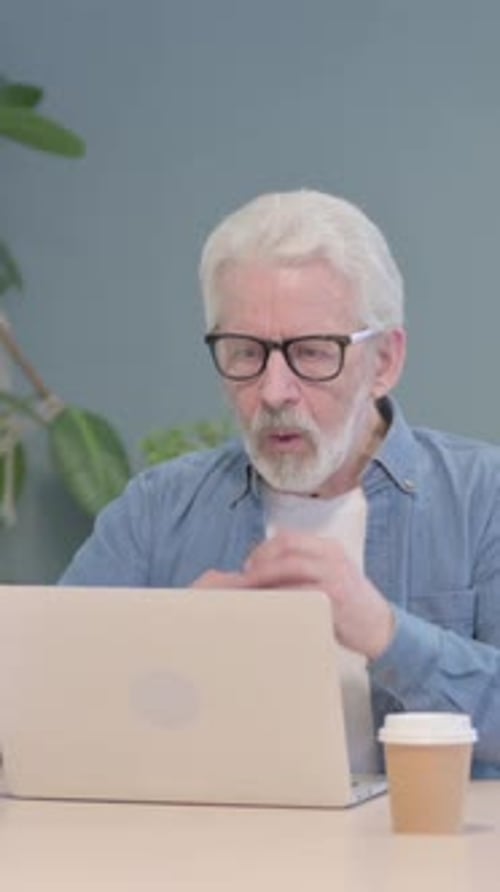 Senior Man Working on Laptop at Desk Indoors