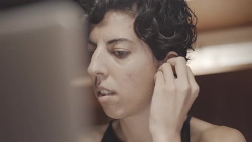 Woman Puts in Wireless Earbud Indoors