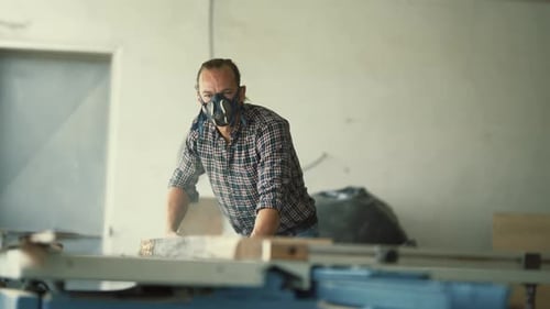 Carpenter with Respirator Mask Working on Table Saw