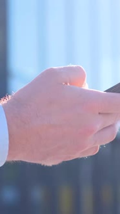 Closeup of a Young Businessman Using a Smartphone Against the Background of a Business Center