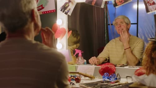 Man with gray hair putting on clown makeup