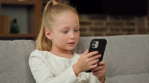 Girl Using Smartphone on Gray Couch Indoors