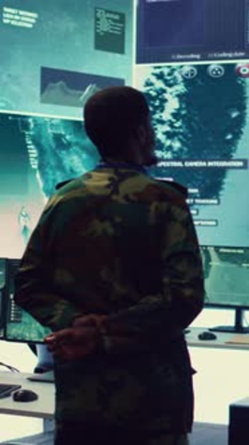 Man in Camouflage Uniform Looks at Monitors