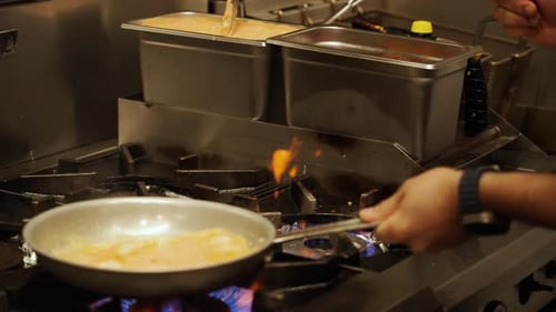 Professional Chef Cooking Meal Over Commercial Kitchen Stove Inside Restaurant. Pan Down Shot
