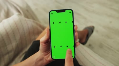 Close up shot of woman using smartphone with mock up green screen at home.