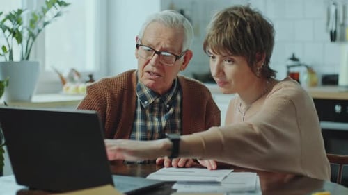 Elderly Man Learning How to Pay Bills Online with Social Worker at Home