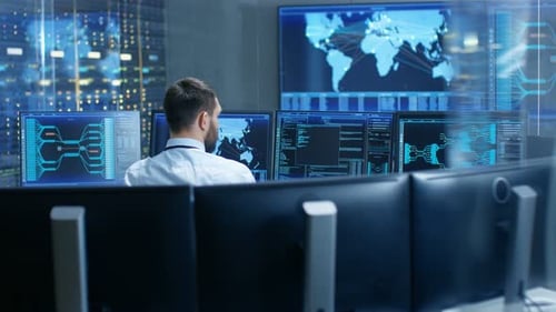 Vista posterior del operador del centro de control del sistema trabajando. Varias pantallas que muestran datos técnicos.