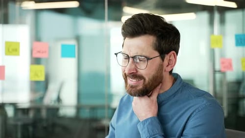 Sick employee suffering from a sore throat while sitting at workplace in a business office
