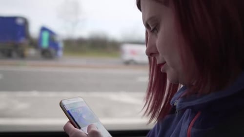 Slow motion close up shot of a girl browsing her smartphone while driving in a vehicle with motion i