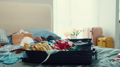 Clothing Falls Into Suitcase on Bed Before a Trip