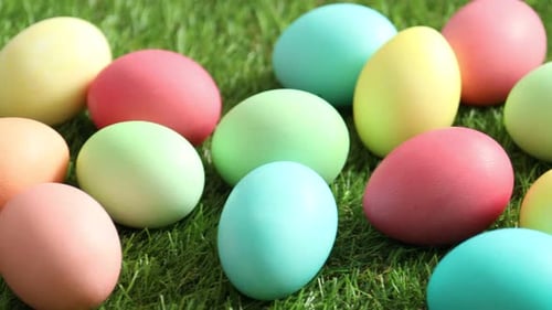 Beautiful decorated Easter eggs on green grass outdoors, closeup. Camera moving right