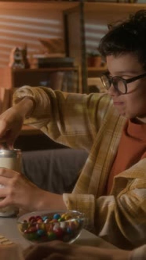 Boy Drinking Beverage With Candy at Desk at Night