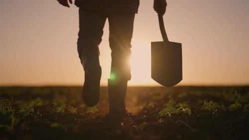 Nahaufnahme von Beinen und Schaufel eines Landarbeiters im landwirtschaftlichen Feld, Silhouette, Landwirtschaft und