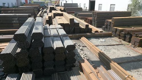 Luftaufnahme von verzinkten Eisenrohren, einem Stapel und rechteckigen Stahlstäben aus Metall