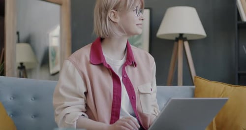 Woman Working on Laptop at Home on Sofa