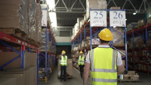 Blue collar workers are working at warehouse.
