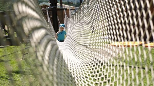 A Little Boy with a Helmet Passes an Obstacle Course in an Amusement Park