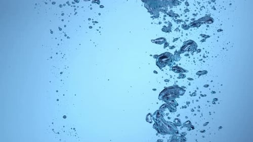 Bubbles rising through blue liquid in slow motion