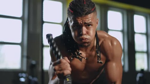 Slow Motion Closeup A Mixed Race Athlete with Dreadlocks on His Head Trains in the Gym with Battle