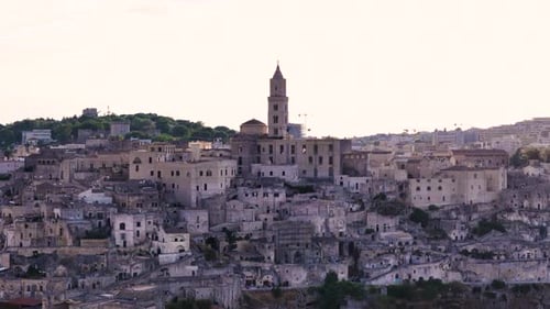 Church tower and downtown of Matera city, sun shines from behind, aerial view